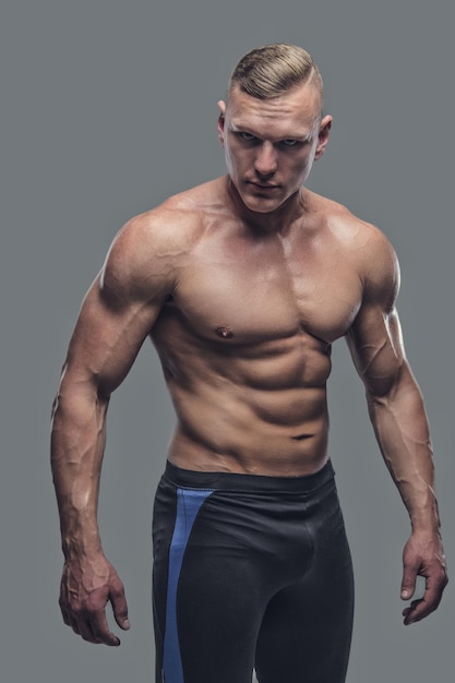 Portrait de femme de fitness torse nu bronzée isolée sur fond gris.