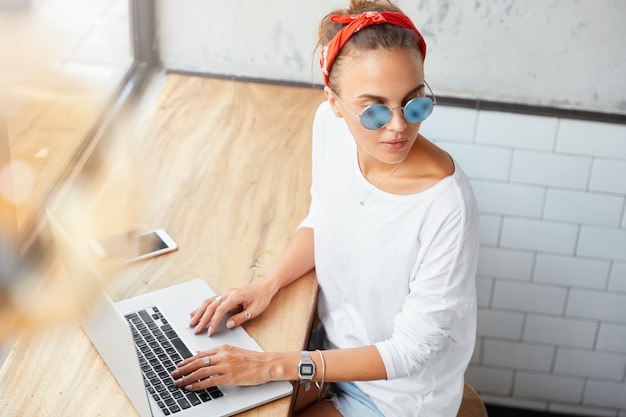 Portrait de femme gestionnaire travaille sur le plan d'affaires à l'ordinateur portable, parcourt les informations, regarde pensivement de côté, entouré de gadgets électroniques modernes. Une rédactrice vérifie le contenu du site Web