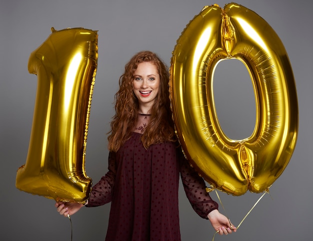 Portrait de femme heureuse avec des ballons en forme de dix