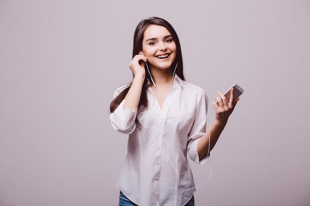 Portrait d'une femme heureuse à l'écoute de la musique dans les écouteurs isolé sur fond blanc