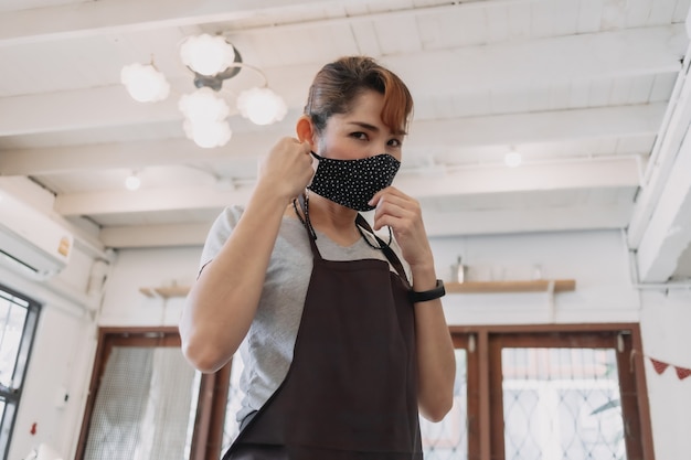 Portrait de femme heureuse propriétaire de café et de restaurant avec masque facial