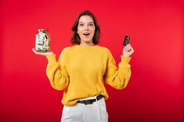 Portrait d'une femme heureuse tenant un pot plein d'argent