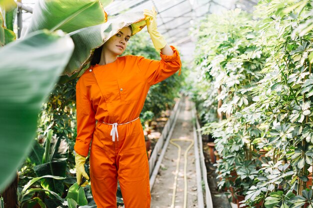 Portrait d&#39;une femme jardinier debout sous une feuille de bananier en serre