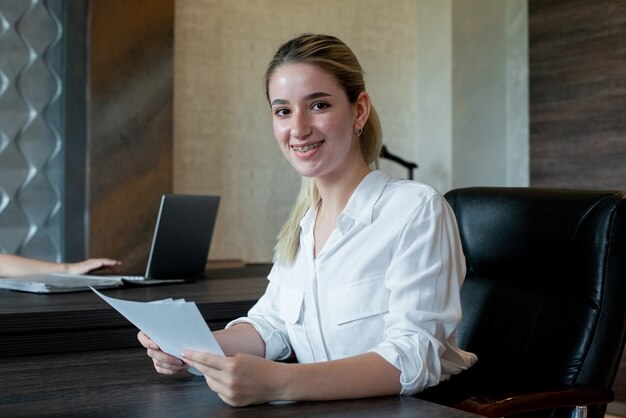 Portrait de femme jeune employé de bureau assis au bureau avec des documents à l'ennui et surmené assis au bureau