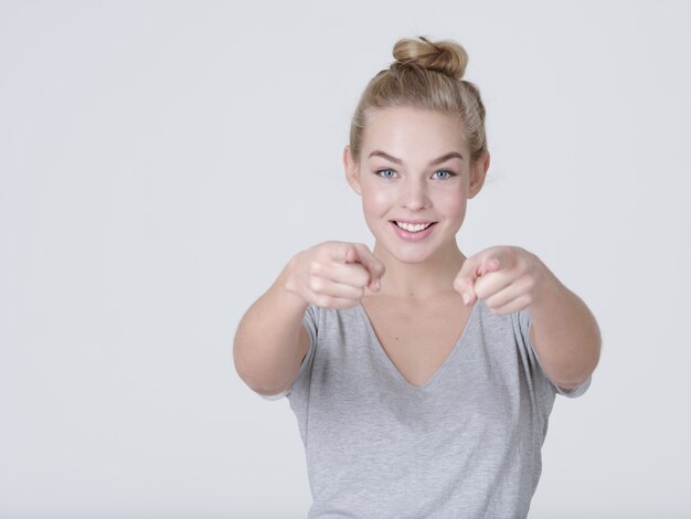 Portrait d'une femme joyeuse pointe vers quelqu'un - sur fond blanc