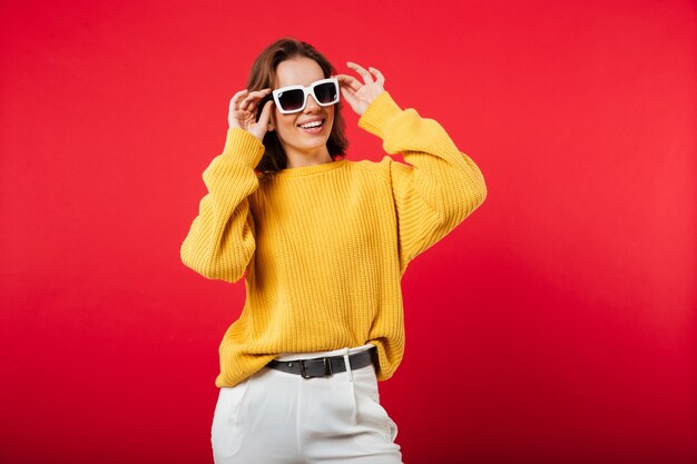 Portrait d'une femme joyeuse en posant des lunettes de soleil