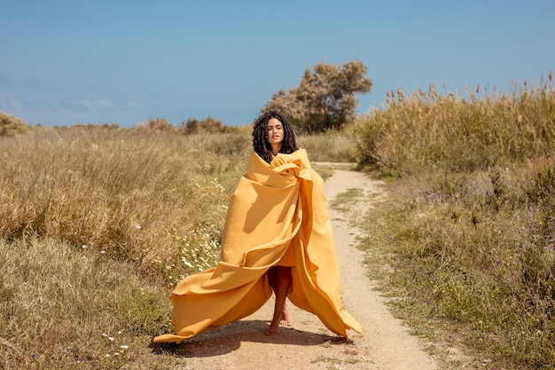 Portrait de femme joyeuse avec un tissu jaune dans la nature