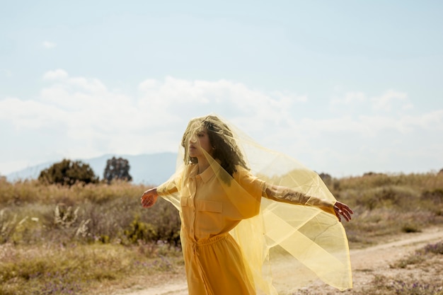 Photo gratuite portrait de femme joyeuse avec un tissu jaune dans la nature