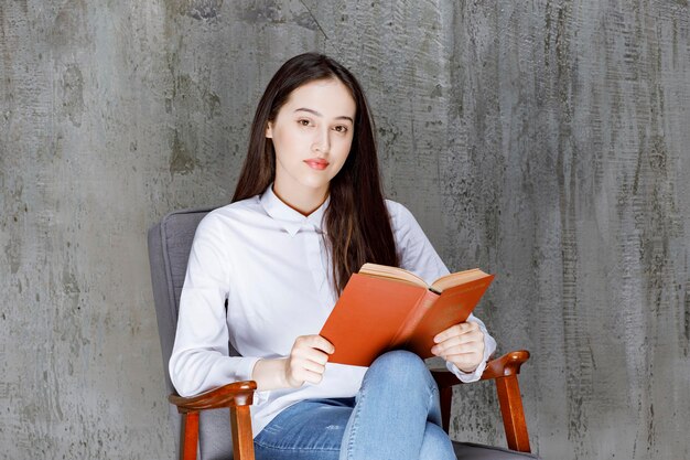 Portrait de femme lisant un livre assis sur un fauteuil. Photo de haute qualité