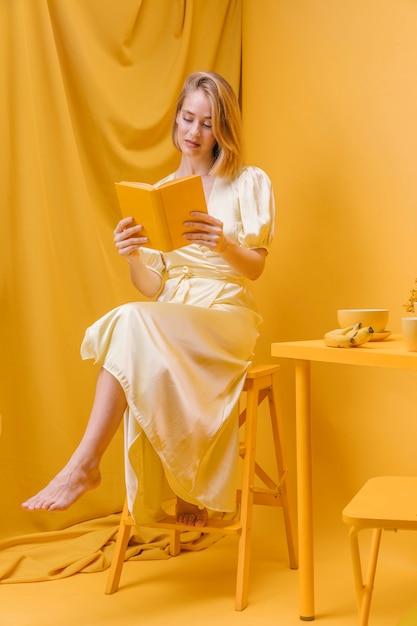 Photo gratuite portrait de femme lisant un livre dans une scène jaune