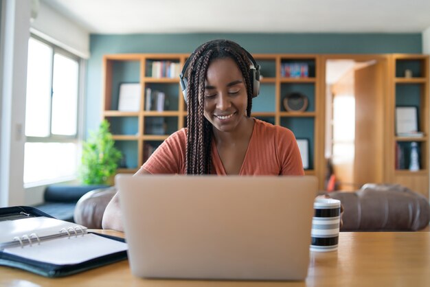 Portrait d'une femme lors d'un appel vidéo avec un ordinateur portable et des écouteurs tout en travaillant à la maison concept