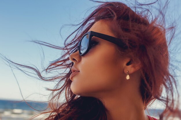 Portrait d'une femme à lunettes de soleil aux longs cheveux bruns.