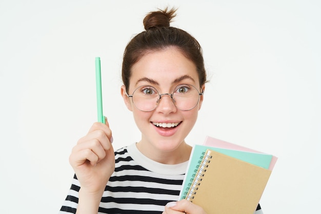 Portrait d'une femme en lunettes. Le tuteur lève la main avec un stylo. Geste eureka. A une idée ou une solution.