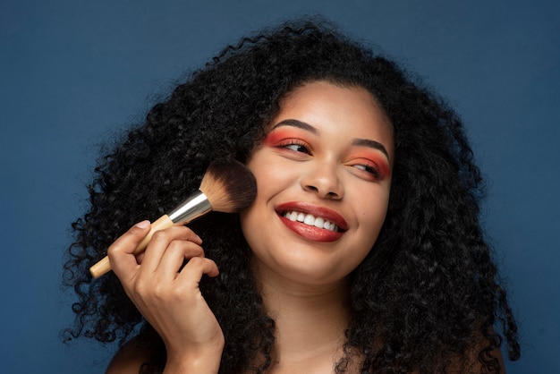 Portrait d'une femme magnifique appliquant le maquillage avec un pinceau de maquillage