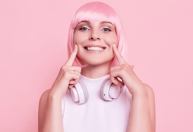 Portrait de femme magnifique aux cheveux roses aime la musique dans les écouteurs