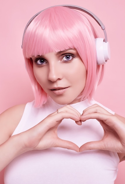 Portrait de femme magnifique aux cheveux roses aime la musique dans les écouteurs