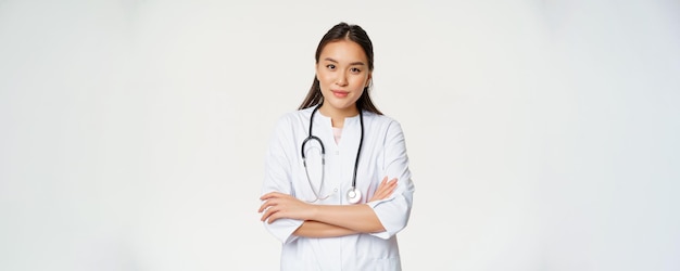 Portrait de femme médecin asiatique bras croisés debout en uniforme médical et stéthoscope souriant à la cam