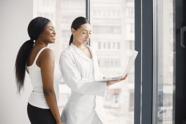 Portrait d'une femme médecin caucasienne et d'un patient noir debout au bureau à la clinique