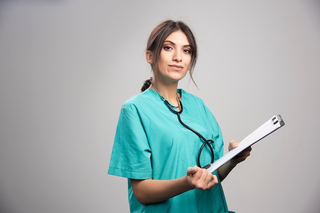 Portrait de femme médecin posant avec presse-papiers sur fond gris