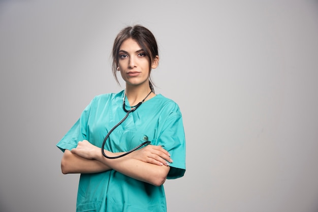 Portrait de femme médecin posant avec stéthoscope sur fond gris