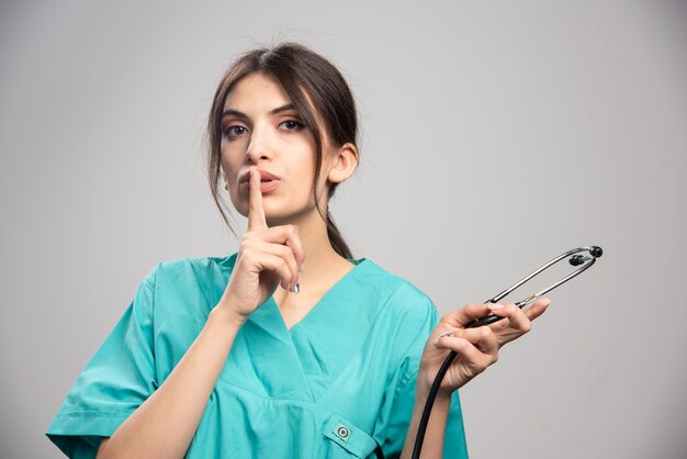 Portrait de femme médecin avec stéthoscope sur fond gris