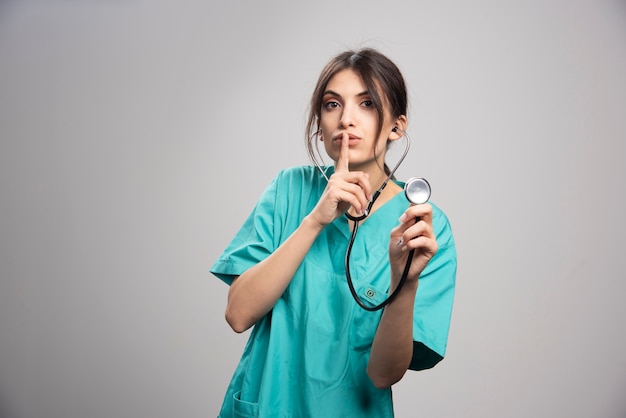 Portrait de femme médecin avec stéthoscope sur fond gris