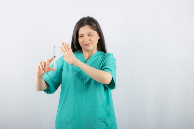 Portrait de femme médecin tenant une grosse seringue.