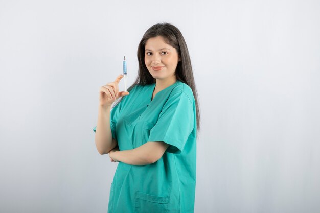 Portrait de femme médecin tenant une grosse seringue.