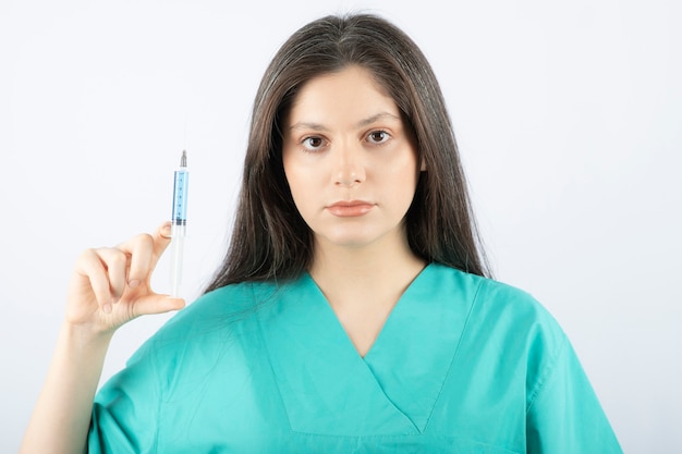 Portrait de femme médecin tenant une grosse seringue.