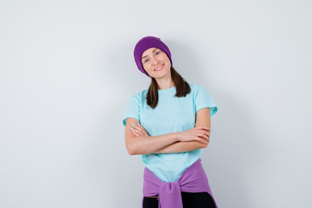 Portrait de femme merveilleuse avec les mains croisées en chemisier, bonnet et à la vue de face confiante