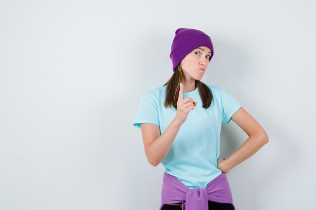 Portrait d'une femme merveilleuse pointant vers le haut en blouse, bonnet et à la vue de face confiante