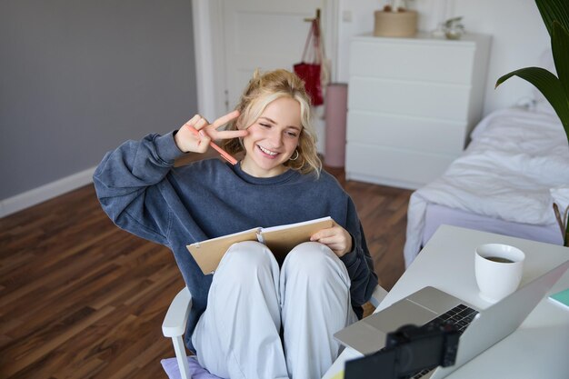 Portrait d'une femme mignonne et souriante blogueuse de style de vie assise dans sa chambre avec un journal quotidien ou un planificateur