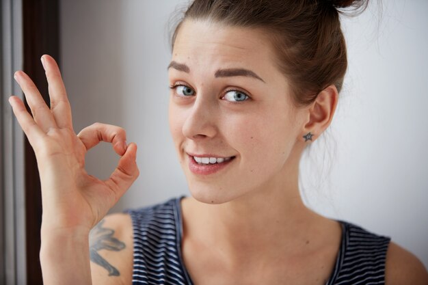 Portrait d'une femme montrant le signe ok et souriant