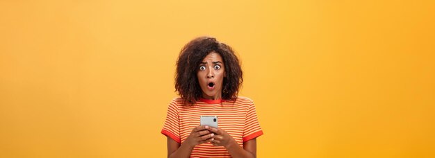 Portrait d'une femme de peau noire choquée et préoccupée avec une coiffure afro et des yeux sautant de