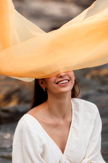 Photo gratuite portrait de femme à la plage cachant son visage derrière un voile