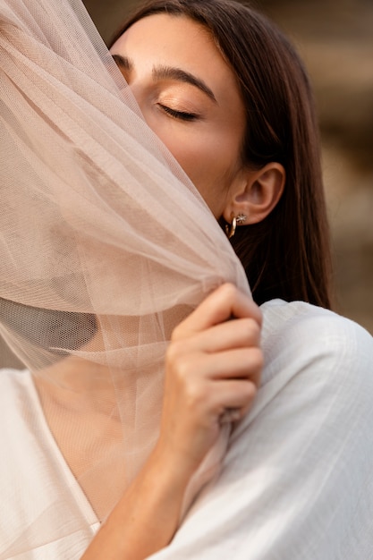 Portrait de femme à la plage cachant son visage derrière un voile