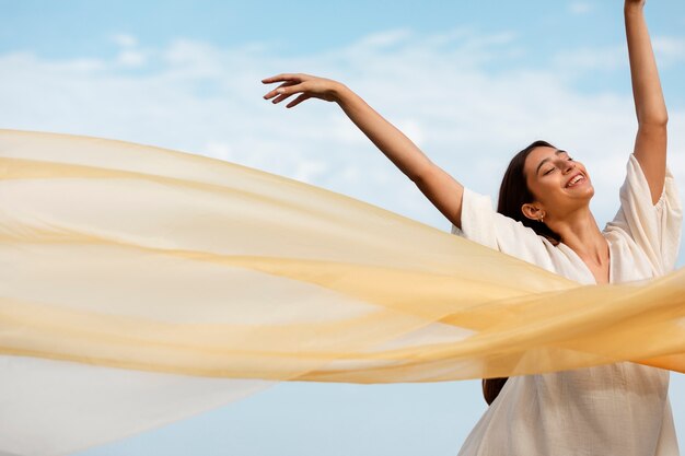 Portrait de femme à la plage posant avec voile