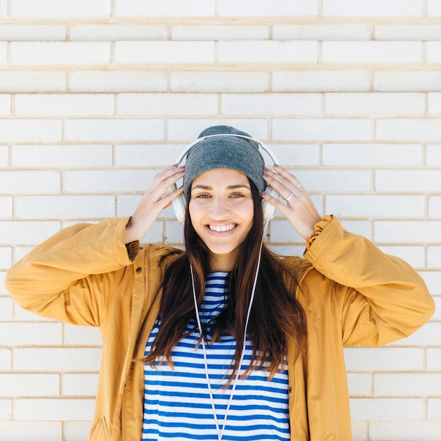 portrait, femme, porter, chapeau tricoté, et, écouteurs, regarder appareil-photo