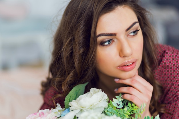 Portrait de femme pose et se détend dans son lit avec des fleurs