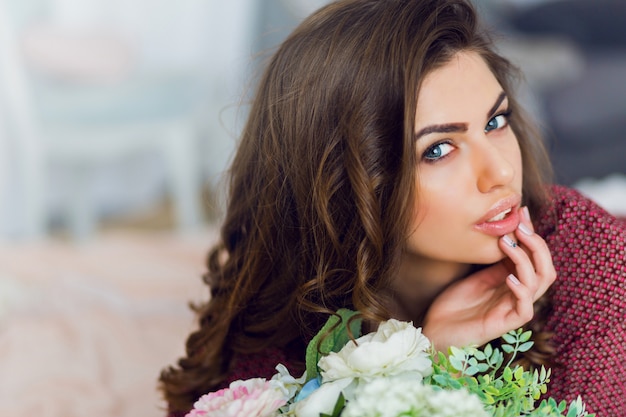 Photo gratuite portrait de femme pose et se détend dans son lit avec des fleurs