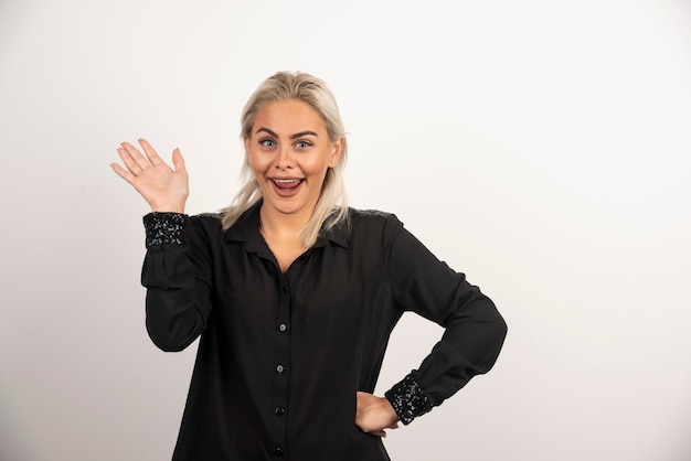 Portrait de femme positive en chemise noire posant sur fond blanc. Photo de haute qualité