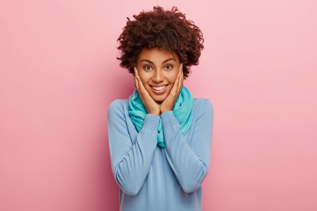 Portrait de femme positive heureuse avec des cheveux naturels, touche les joues