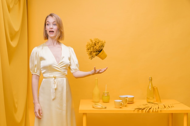 Photo gratuite portrait de femme avec un pot de fleur dans une scène jaune