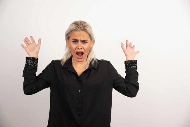 Portrait de femme qui crie en chemise noire posant sur fond blanc. Photo de haute qualité