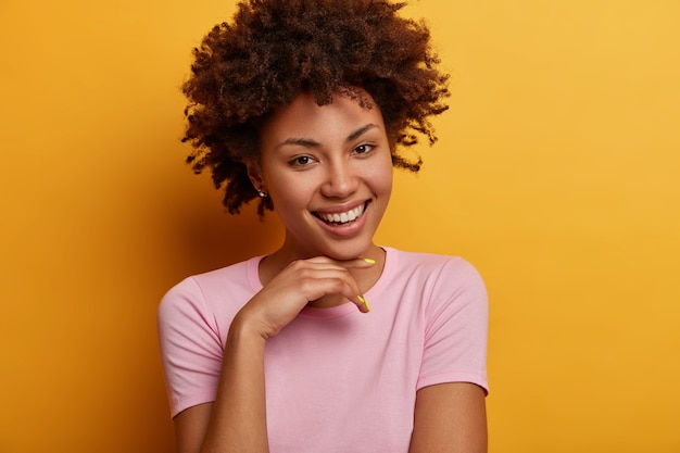 Photo gratuite portrait de femme à la recherche amicale optimiste tient la main sous le menton