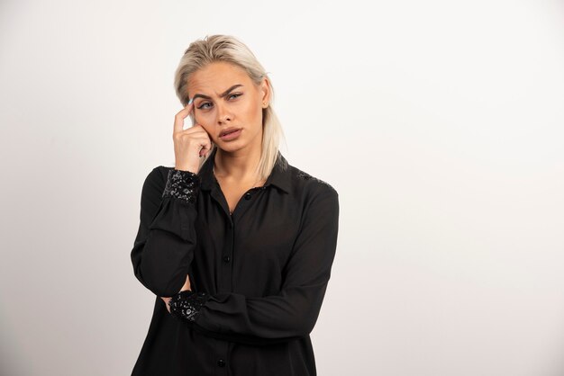 Portrait de femme réfléchie en chemise noire posant sur fond blanc. Photo de haute qualité