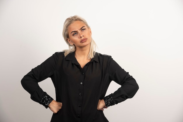 Portrait de femme réfléchie en chemise noire posant sur fond blanc. Photo de haute qualité