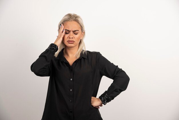 Portrait de femme réfléchie en chemise noire posant sur fond blanc. Photo de haute qualité