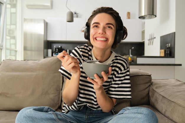 Photo gratuite portrait d'une femme regardant la télévision dans des écouteurs sans fil regardant l'écran avec intérêt et excitation