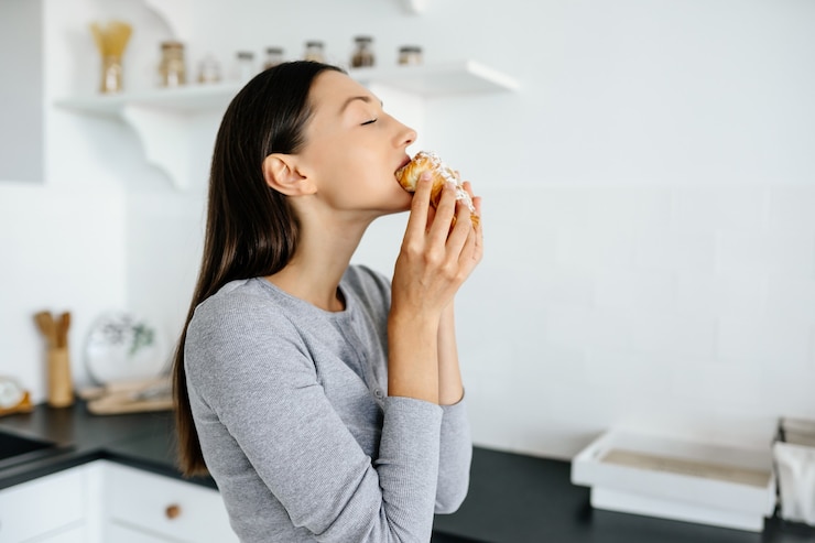 Photo gratuit portrait de femme réjouissante mange de délicieux croissants à la maison. concept de nourriture malsaine.